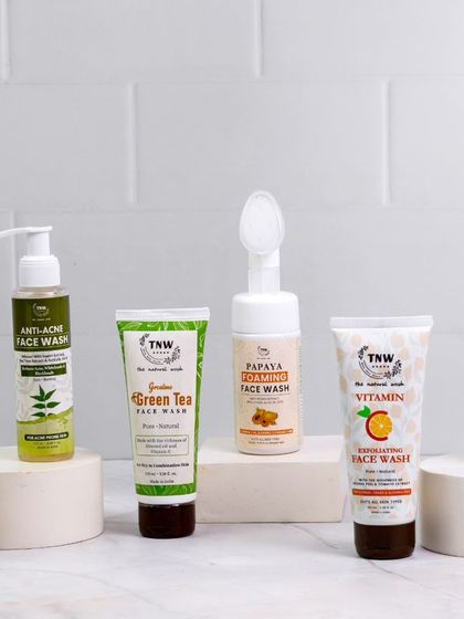 This group shot of various face washes is styled on white podiums, creating a clean, gallery-like feel. The arrangement highlights the diversity of the product line, from tubes to pump bottles.