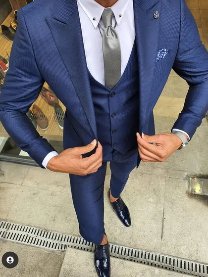 A perfectly tailored three piece suit is a must have for any man's wardrobe. This slim fit navy blue suit, shown here with a matching waistcoat and a crisp white shirt, is ideal for business meetings, weddings, or any formal event where you need to look your best.