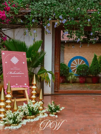 The entrance to a Muhurtham ceremony, marked by a simple yet elegant sign and traditional brass decor elements.