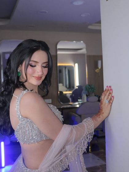 A candid moment captured in the studio. The soft lighting highlights the dewy finish of her makeup and the intricate details of her hairstyle.