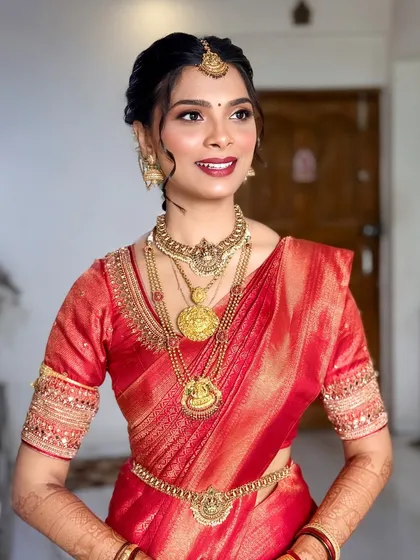 A radiant South Indian bride in a stunning red silk saree. The makeup features a classic red lip and defined eyes, perfect for her wedding day.
