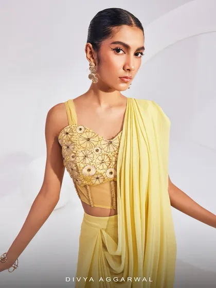 The Isla Saree Set in a beautiful yellow, featuring a dhoti-style pre-draped saree and a corset blouse with exquisite embellishments and a tulle net design.