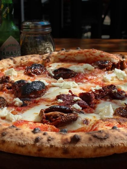The Smokey Marzano pizza, featuring sundried tomatoes, garlic, feta, and our hand-stretched mozzarella on a sourdough crust. The wood-fired oven gives it a subtle smoky flavor.