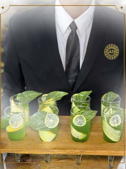 A server presents our refreshing mocktails, garnished with fresh basil and lime. These drinks are crafted to be as visually appealing as they are delicious.