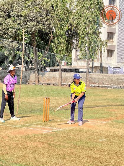A female batter prepares to face a delivery, demonstrating her batting stance and focus.