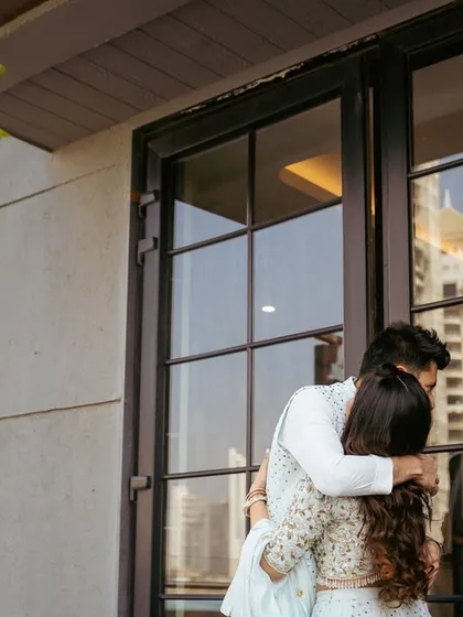 A heartfelt hug on a balcony overlooking the city. A private moment of connection against a public backdrop.
