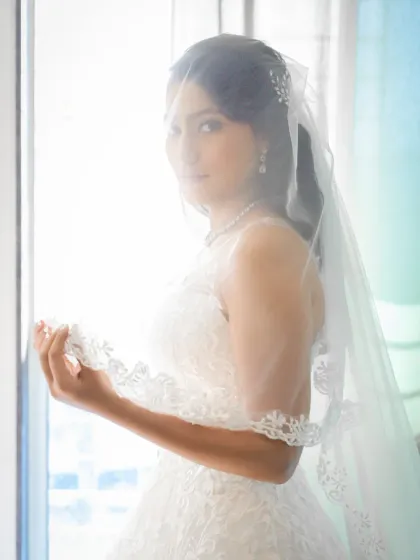 A dreamy and artistic bridal portrait, with the bride looking through her veil. The bright, soft light creates an ethereal and romantic mood.