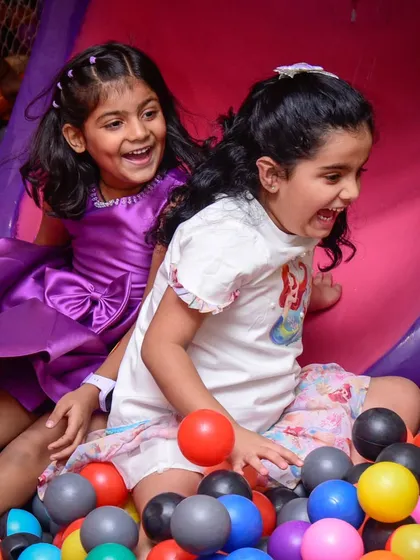 Pure, unfiltered joy! Two girls laughing as they play in the ball pit.