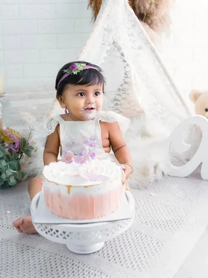 A delicate moment from a boho-chic cake smash session. This little girl is just about to dig into her beautiful first birthday cake.