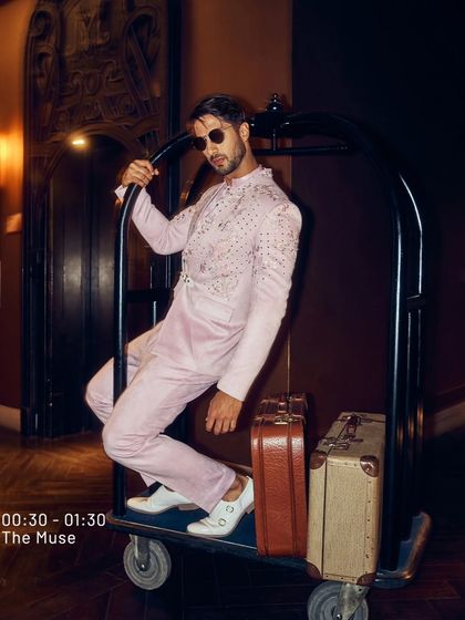 Taking steps that speak volumes. This blush pink ensemble, complete with vintage luggage, is for the man who conquers with style and moves with grace.