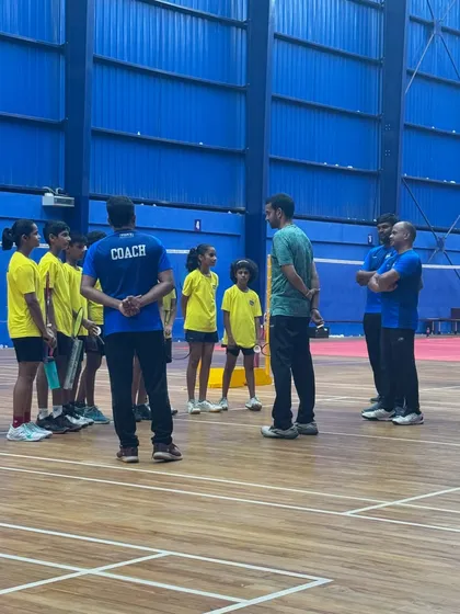 A huddle on the court where Mr. Gopichand provides direct feedback and strategy to a group of young players and coaches.