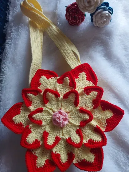 A detailed shot of the Lotus Bag against a soft background, with some crochet roses to complement the floral theme.