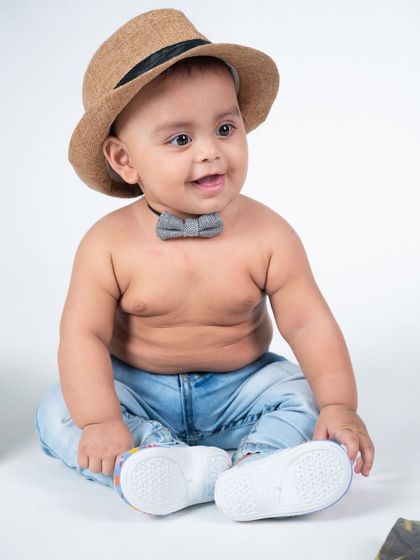 A classic, happy portrait of a toddler boy in a simple studio setting, showing off his cheerful smile.
