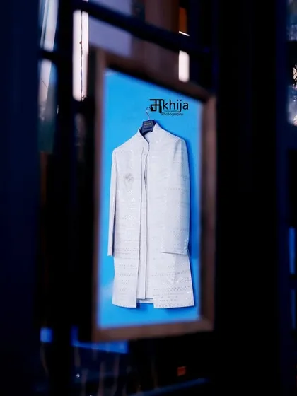 A creative shot of the groom's wedding sherwani. The reflection and deep blue tones create an artistic and moody photo that builds anticipation for the groom's appearance.