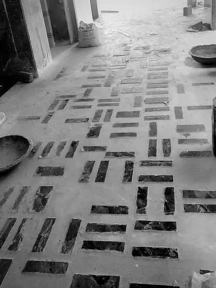 Laying out a modern geometric pattern with stone inlays on the floor of our Delhi project. This black and white shot shows the process of setting the dark stones into the concrete base.