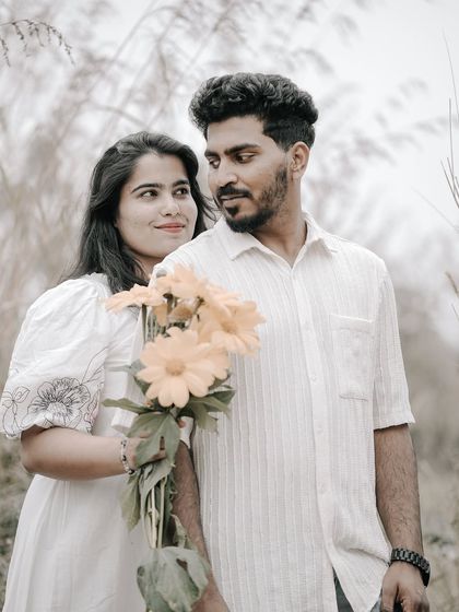 A sweet portrait of a couple in a field, the bride holding a bouquet of yellow flowers, sharing a look.