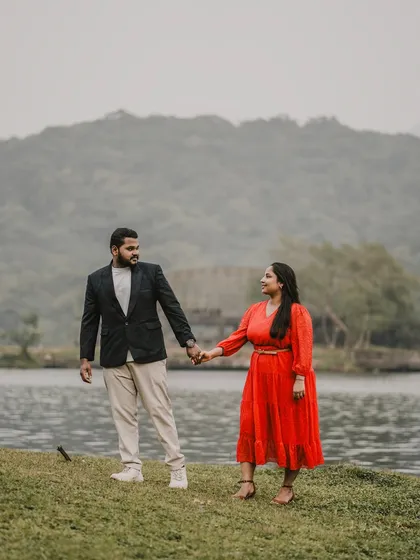 Holding hands by the water's edge with the lush green hills as a backdrop. This showcases the serene beauty of Maharashtra's landscapes.