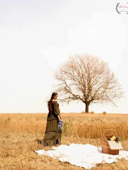 A beautiful pregnancy announcement shoot in a golden field with actress Shireen Mirza, holding her first ultrasound picture.