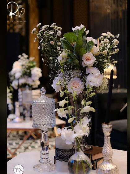 A centerpiece of white and blush roses with orchids, set in a crystal-cut vase. The details add a layer of sophistication.