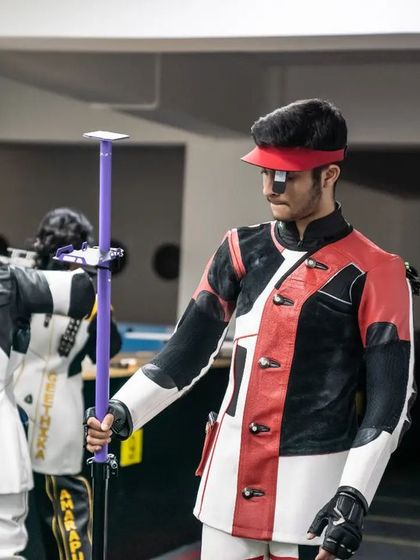 An athlete stands ready with his rifle support stand, a piece of essential equipment for 3-position shooting.