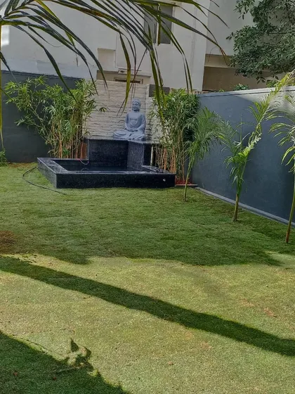 Another view of the completed landscape, highlighting the contrast between the dark grey boundary wall and the vibrant green of the new lawn and plants.