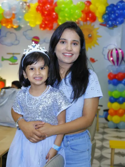 A mother and her daughter, the birthday princess, share a smile at a colorful party.