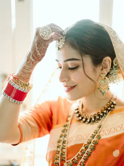 This look was all about capturing elegance through simplicity. For Arundhati, who was hesitant about professional makeup, we created a minimal look with radiant skin, a delicate liner, and the perfect pink lip to match her beautiful orange saree.