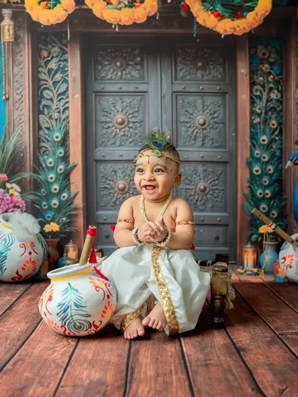 A wide shot showing the full, vibrant Janmashtami setup with a very happy baby.