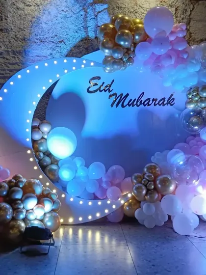 For a modern Eid celebration, I designed this beautiful photo booth. It features a large crescent moon with built-in lights, surrounded by a cascade of pastel and gold balloons for a festive and stylish look.