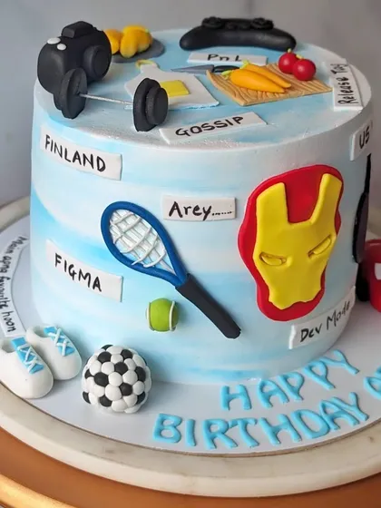 This cake was designed for a colleague's birthday, covered in all his favorite things. This view shows his love for tennis, Figma, and inside jokes like "Gossip" and "Arey."