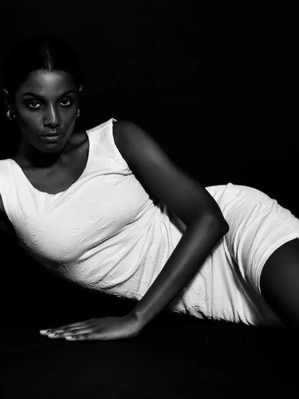 A powerful and alluring pose on the floor, with the high-contrast lighting highlighting the model's form.