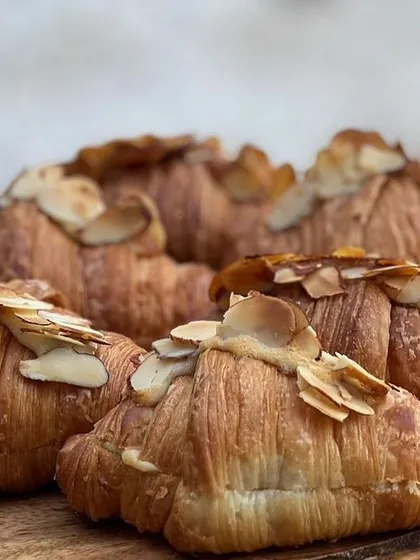 Flaky, buttery almond croissants, perfect for a breakfast meeting or a high-tea event.