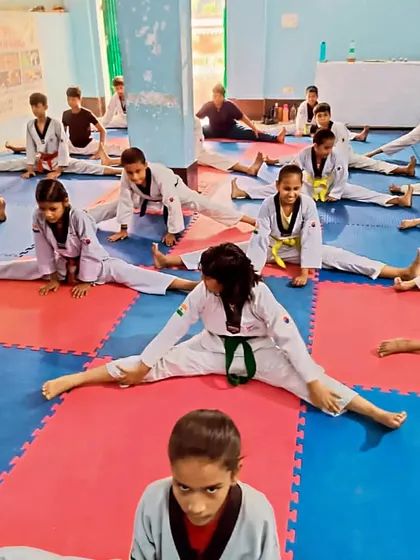 A group of students holding a deep stretch. Consistent stretching is essential for achieving high kicks.