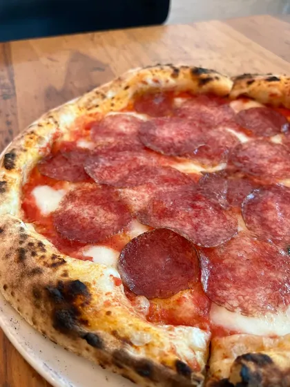 A side view of the Hungarian Salami pizza, highlighting the puffy, charred cornicione.