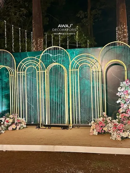 A stylish selfie point with a marble-effect green backdrop, gold geometric arches, and lush floral arrangements.