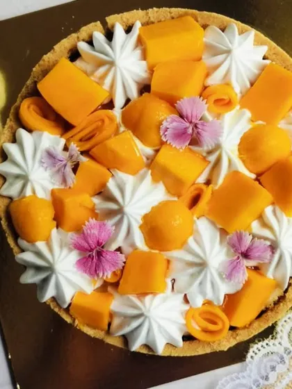 An overhead view of the Mango Cheesecake, showing the beautiful arrangement of mango pieces and edible flowers on a bed of whipped cream.