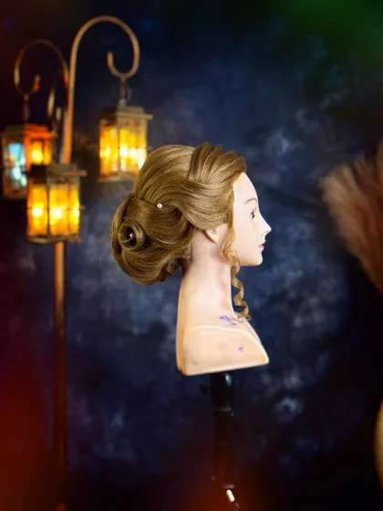 A side profile of a classic chignon with a modern twist. Our curriculum balances timeless techniques with contemporary trends in hairstyling.