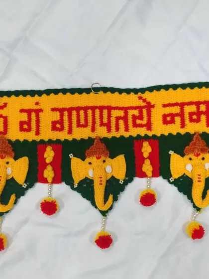 This photo shows the Ganpati toran ready to be hung, with small rings crocheted into the top for easy installation on any door frame.