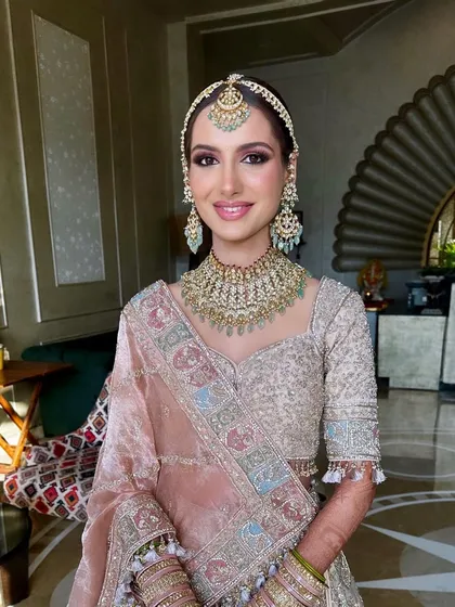 A close-up of the summer bridal makeup. The look features soft pink eyeshadow and a luminous base, perfectly complementing her pastel outfit and mint green jewelry.