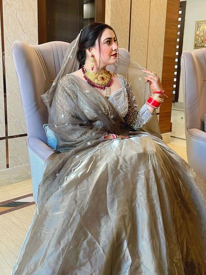 A regal pose from this beautiful bride. Her grey organza lehenga is paired with a statement gold and red necklace and matching bold makeup.