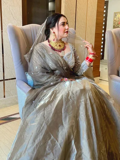 A seated portrait of a bride in her grey lehenga. The makeup is classic and elegant, with a focus on her eyes.