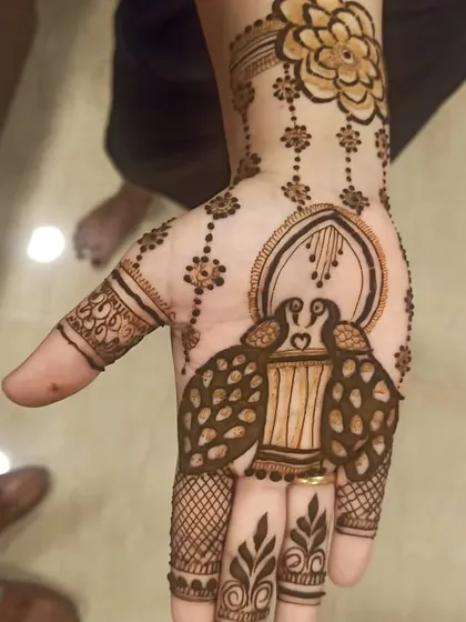A simple yet charming design with two peacocks forming a heart. This minimalist style is perfect for guests who prefer lighter henna work.