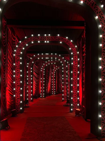 The entrance tunnel for a Las Vegas themed party. I used repeating arches lined with bright bulbs and draped in rich red fabric to create a dramatic and glamorous pathway for guests.