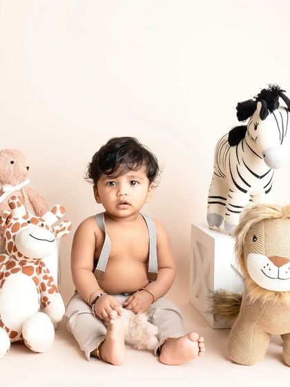 This little boy is sitting proudly with his stuffed animal collection. The simple, clean setup allows his personality and his favorite toys to be the stars of the show.