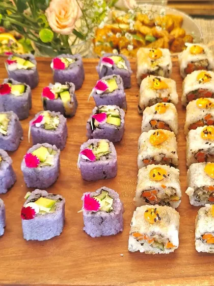 A platter of our colorful sushi rolls, featuring both purple and white rice varieties. Garnished with edible flowers, this is a perfect example of our "Pinterest-worthy" presentation.