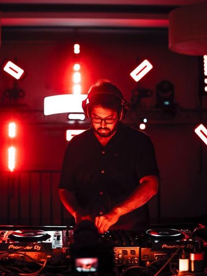 A DJ at work, with the red lighting creating a moody and intense vibe. We curate every element of the night to build a specific atmosphere.