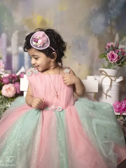 This toddler is adjusting her floral headband, a sweet, candid moment from the painted garden session.