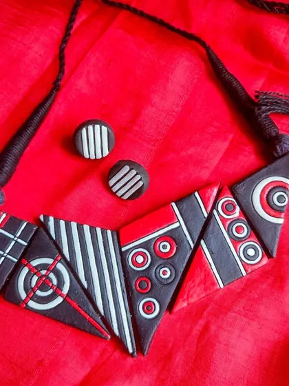 This bold, geometric necklace is perfect for pairing with a western outfit. The abstract design is made of triangular pieces in a striking red, black, and white combination.