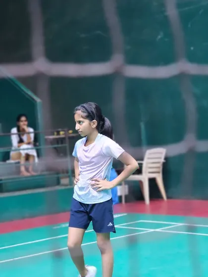 A young girl stands ready on the court, focused and prepared for her turn in the drill.