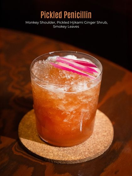 The Pickled Penicillin, a tangy and smoky creation. Monkey Shoulder whisky is paired with a pickled hijikami ginger shrub and smoky leaves for a truly unique taste.